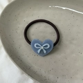 Détail d'un charme cœur bleu avec nœud et strass sur un élastique à cheveux noir - Bleu