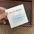 Primer plano de dos pinzas para el cabello azul mate en la tarjeta del embalaje - Azul