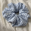Detail of blue and white striped fabric scrunchie with soft ruffled texture and small label - Puff Stripe