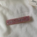 Makro-Detail einer rosa Haarspange aus Acetat mit silbernem Blumenmuster und Strass - Rosa