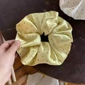 Close-up of a large yellow satin scrunchie with black polka dots and silky texture - Yellow