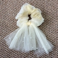 Detail von cremefarbenem Organza-Haargummi mit langen Netzbändern und feinen Kunstperlen - Gansgelb