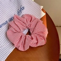 Detail van rood-witte gingham haarelastiekje op houten tafel bij natuurlijk licht - Rood
