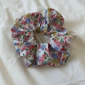 Detail van de bloemrijke scrunchie in olieverfstijl met roze bloemen en een merklabel - Kleurrijk