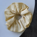 Détail macro du chouchou en tissu à rayures jaunes et blanches avec texture plissée - Jaune