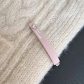 Detail shot of a pink heart-shaped rhinestone hair clip with white text on a knit background - Pink
