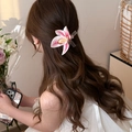 Detail of a pink magnolia flower hair clip with translucent ribbon on long wavy hair - Pink