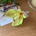 Close-up of artificial magnolia hair clip with yellow-green petals and ribbon on wood - Yellow-Green
