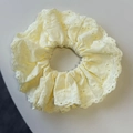 Detailed macro view of pale yellow cotton scrunchie featuring elegant eyelet embroidery - Yellow