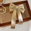 Detailansicht einer champagnergoldenen Haarklammer aus Metallic-Stoff mit Schleife - Champagner
