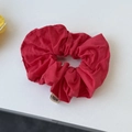 Detail of red oversized scrunchie in thick cotton fabric with a white woven brand label - Red