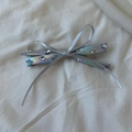 Detail view of silver PU leather bow hair clip with sparkling rhinestones on white fabric - Double Bowknot Hair Clip