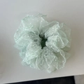 Close-up of mint green polka dot mesh hair scrunchie with lace ruffle edge and soft texture - Green