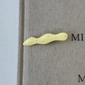Detailed view of wave-shaped yellow hair clip with blue polka dots on grey fabric - Yellow Wave