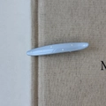 Close-up of light blue resin hair clip with white polka dots on a textured background - Blue Willow