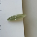 Close-up of translucent olive green oval hair clip with fine glitter on a book page - Green