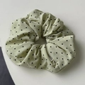 Detail shot of mint green fabric scrunchie with small black heart patterns and woven label - Green Scrunchie