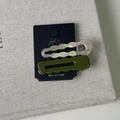 Detail of pearlescent pink wavy acetate hair clip and olive green H letter hair pin - Green System