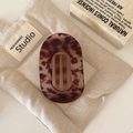 Close-up of tortoise shell oval hair claw clip with cutout design on vintage linen - Matte Tortoiseshell