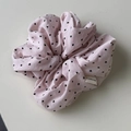 Détail d'un chouchou en tissu rose avec motif cœur et étiquette de marque tissée sur blanc - Rose