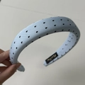 Détail d'un serre-tête rembourré bleu clair avec motifs cœurs noirs et étiquette - Serre-tête Bleu