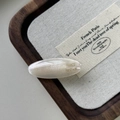 Dettaglio del fermaglio ovale in acetato crema con scritta dorata France Handmade - bianco sirena