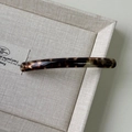 Macro detail of tortoiseshell acetate barrette hair clip with France lettering logo - Amber