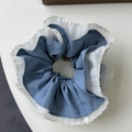 Macro detail of large blue fabric scrunchie with white sheer mesh and delicate lace edges - Blue