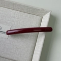 Macro shot of glossy dark red acetate hair clip with golden Barrette La France lettering - Red
