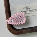 Dettaglio del fermaglio a cuore rosa con strass colorati su un vassoio di legno - Rosa