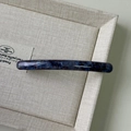 Detail of blue purple marbled acetate hair clip with elegant glossy texture on beige tray - Blue and Purple