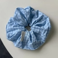 Vista detallada del coletero scrunchie a cuadros azul claro con etiqueta artesanal - Coletero / Azul