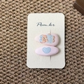 Dettaglio di fermagli per capelli in tessuto rosa con orsetto e cuori blu decorati - Orso con Vestito