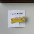 Close-up of wave-shaped resin hair clips in amber marble and yellow on a card - Yellow Series