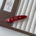 Dettaglio di fermaglio per capelli rosso con motivo floreale in strass in portagioie - Rosso