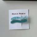 Macro detail of wave-shaped marble texture and blue acetate hair clips on card - Blue Series