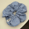 Gros plan du chouchou à rayures bleues et blanches montrant le tissu et le logo nœud - Rayé Bleu Foncé