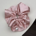 Primer plano detallado de un coletero de satén rosa con una gran perla brillante decorativa - Grande / Rosa