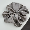 Vue macro détaillée d'un chouchou en satin gris argenté avec des plis doux et brillants - Champagne