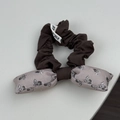 Vue détaillée d'un chouchou à nœud marron et floral rose avec une étiquette tissée - Chouchou Noeud Gris