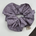 Gros plan détaillé d'un chouchou à fleurs mauves avec une étiquette tissée - Violet