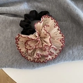 Detailopname van witte bloemen-scrunchie met rode geschulpte randen op grijze stof - Haarelastiek