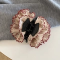 Detail van bloemen haarklem met geploofde stof en rode geschulpte randafwerking - Haarklem