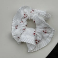 Dettaglio di uno scrunchie bianco con fiori rossi e bordi in pizzo plissettato - Stile Bordo Plicsettato Floreale Rosso