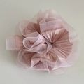 Detail van een lichtroze organza scrunchie met geplooide lagen en bloemige textuur - Roze