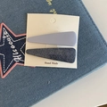 Detail van denim textuur en mat paarse haarclipset op handgemaakte kartonnen kaart - Driehoekstijl