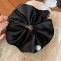 Dettaglio di scrunchie in raso nero con texture liscia del tessuto e decorazione di perle - Nero