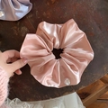 Dettaglio di un elastico in raso rosa con perla bianca su una superficie in legno scuro - Rosa