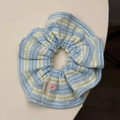 Dettaglio dell'elastico per capelli a righe blu con bottone rosa ed etichetta Hand Made - Scrunchie Blu