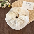 Detail of white embroidered scrunchie with layered lace and pleats on wooden background - Skirt Ruffle Style